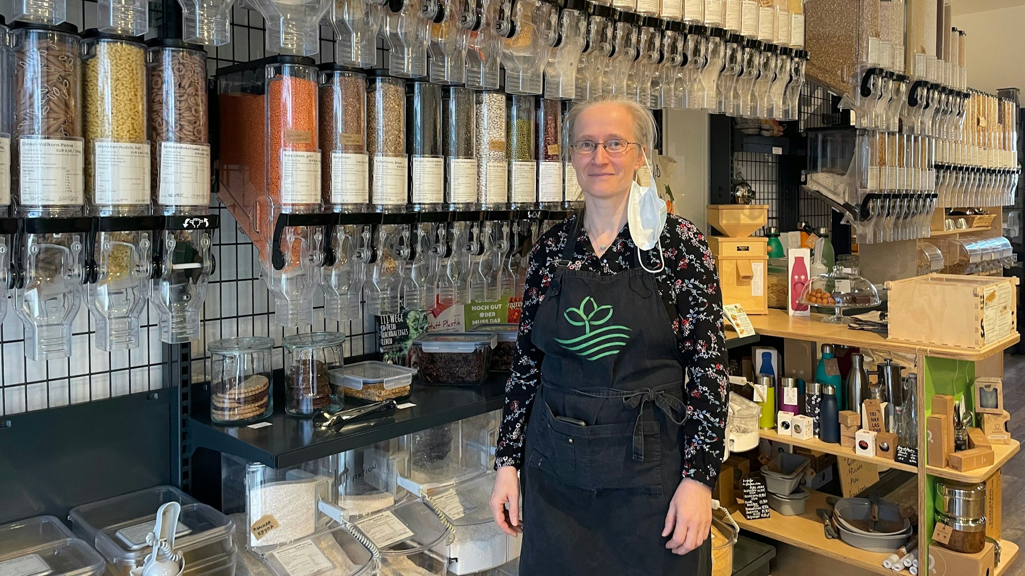 Jana Nehrlich steht in ihrem Geschäft „Zollstock Unverpackt“. Hinter ihr sind viele Behälter mit Waren zu sehen.