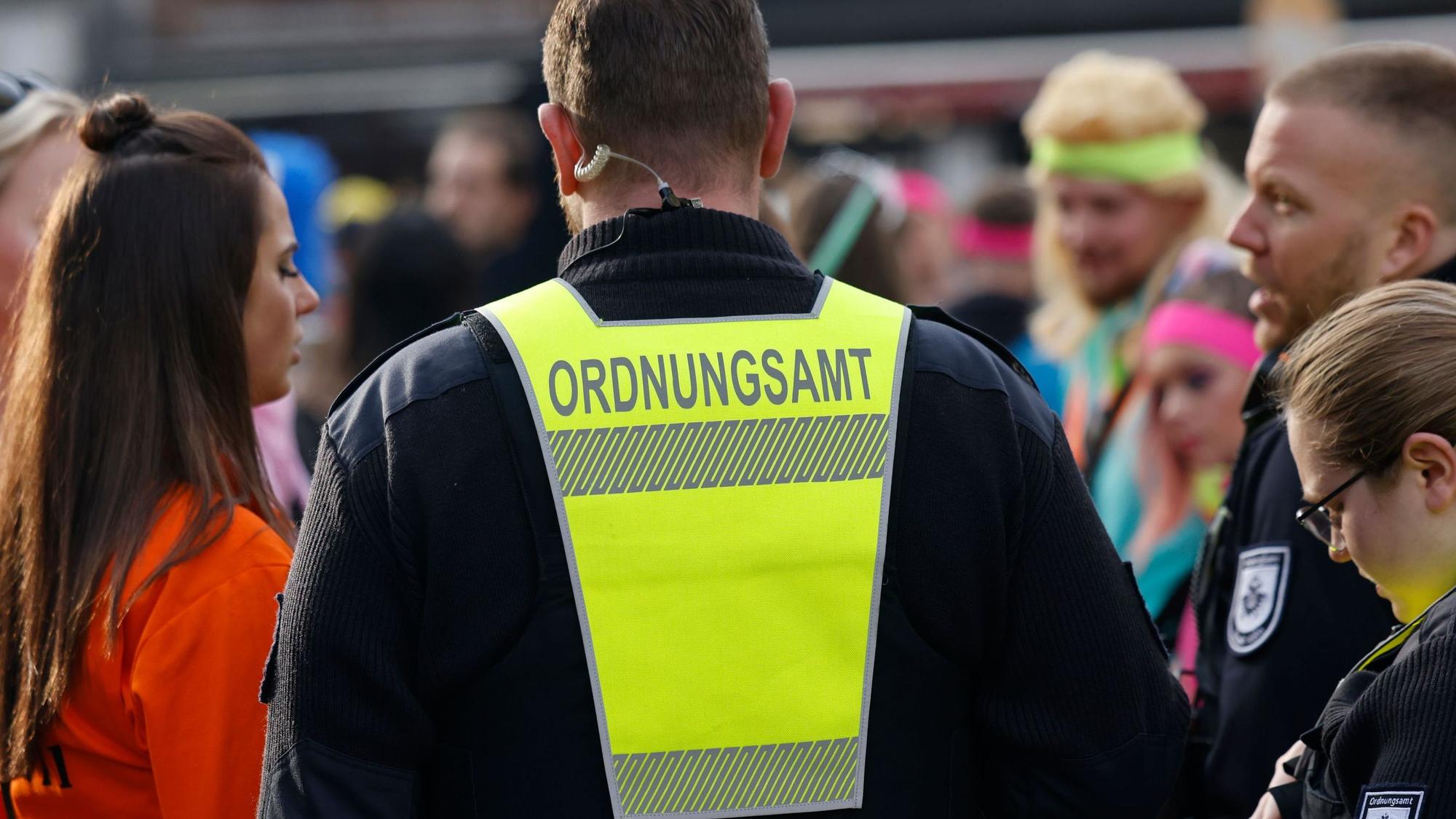 Zwei Mitarbeiter des Ordnungsamts im Gespräch mit Feiernden.