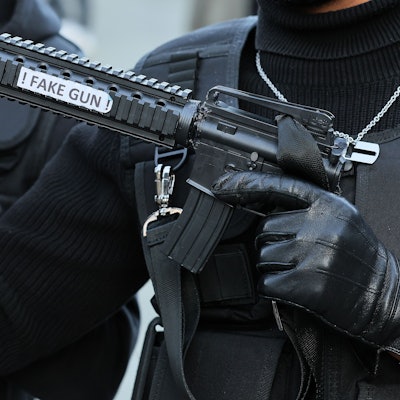 Ein als Swat-Polizist verkleideter Karnevalist hält eine Pistolenattrappe mit der Aufschrift „Fake Gun“ in der Hand.