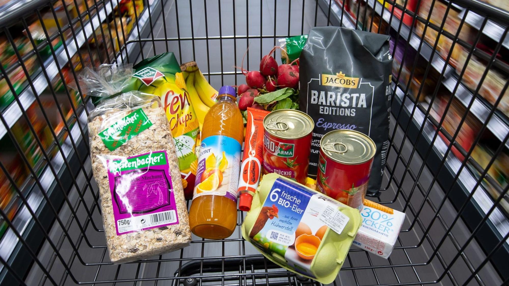 Verschiedene Lebensmittel liegen in einem Supermarkt in einem Einkaufswagen.