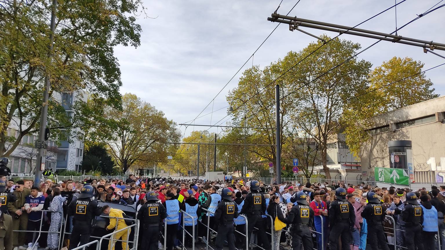 Hunderte junge Leute drängen auf die Absperrungen an der Zülpicher Straße. Die Sicherheitskräfte in blauen Westen haben große Mühe, die Menschen zurückzuhalten.
