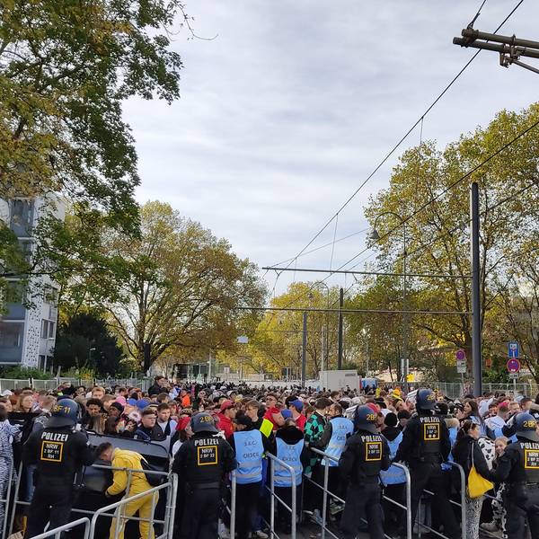 Hunderte junge Leute drängen auf die Absperrungen an der Zülpicher Straße. Die Sicherheitskräfte in blauen Westen haben große Mühe, die Menschen zurückzuhalten.