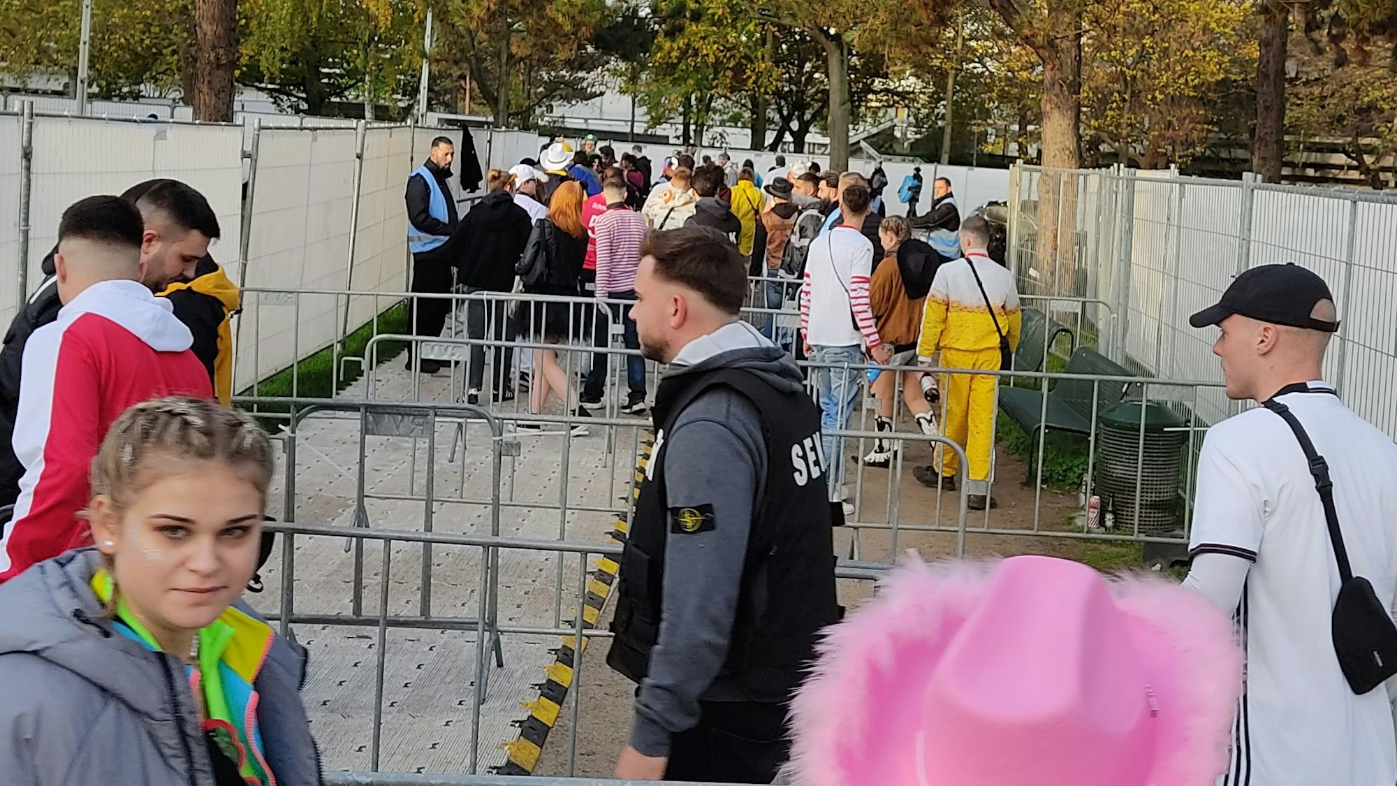 Menschen stellen sich an. Drängelgitter stehen aufgereiht dazwischen.