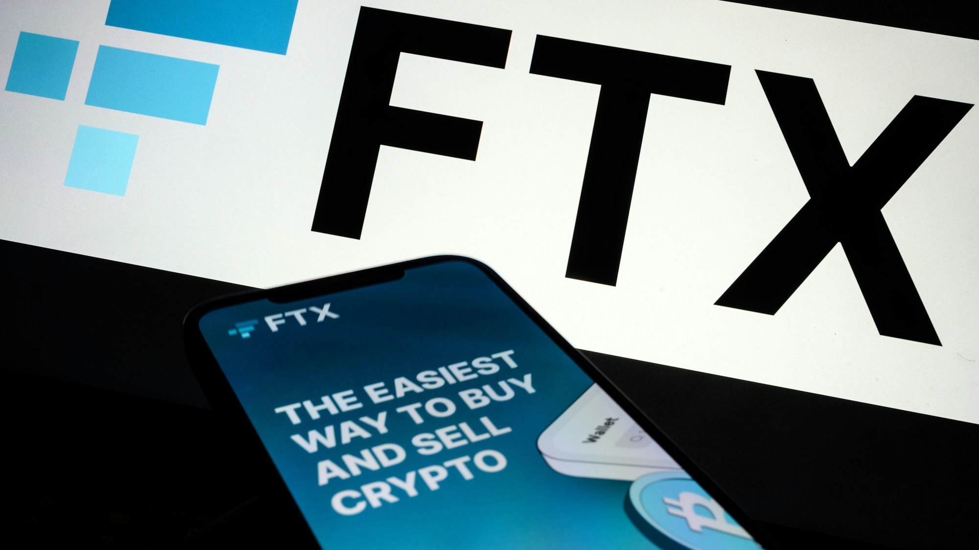 Das Logo der Kryptobörse FTX und die App der Börse auf einem Handy.