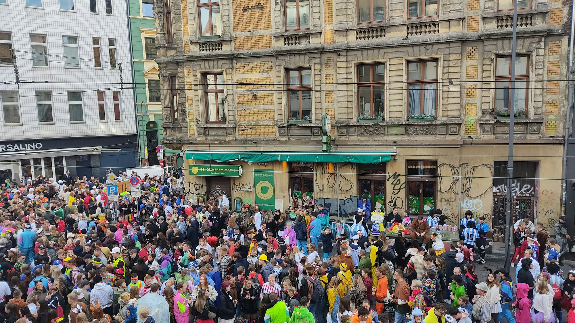 Die Gaststätte Oma Kleinmann am Elften Elften umringt von einer Menschenmasse aus verkleideten Feiernden.