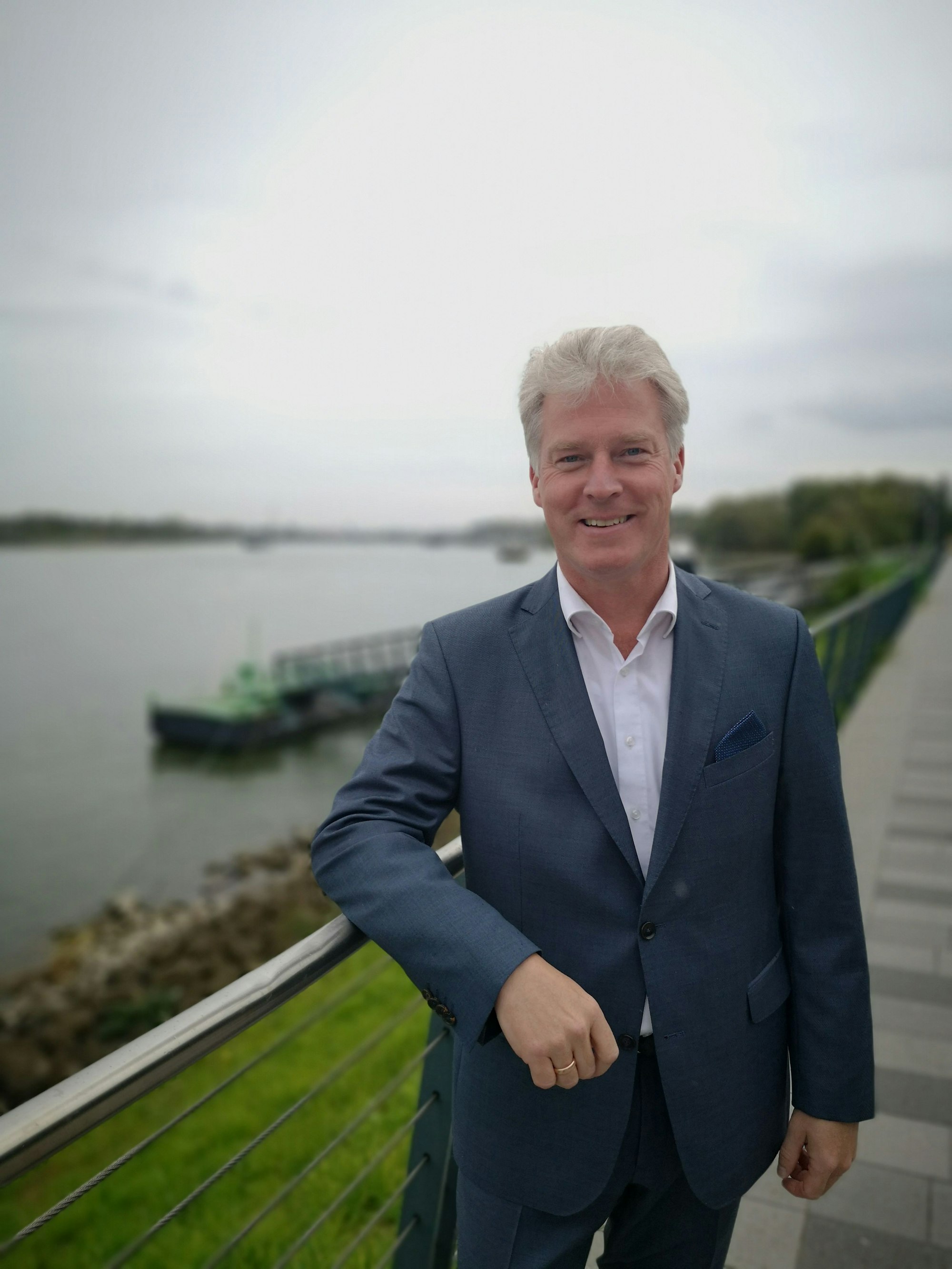 Olaf Kraf steht an ein Geländer gelehnt. Hinter ihm ein Fluss.