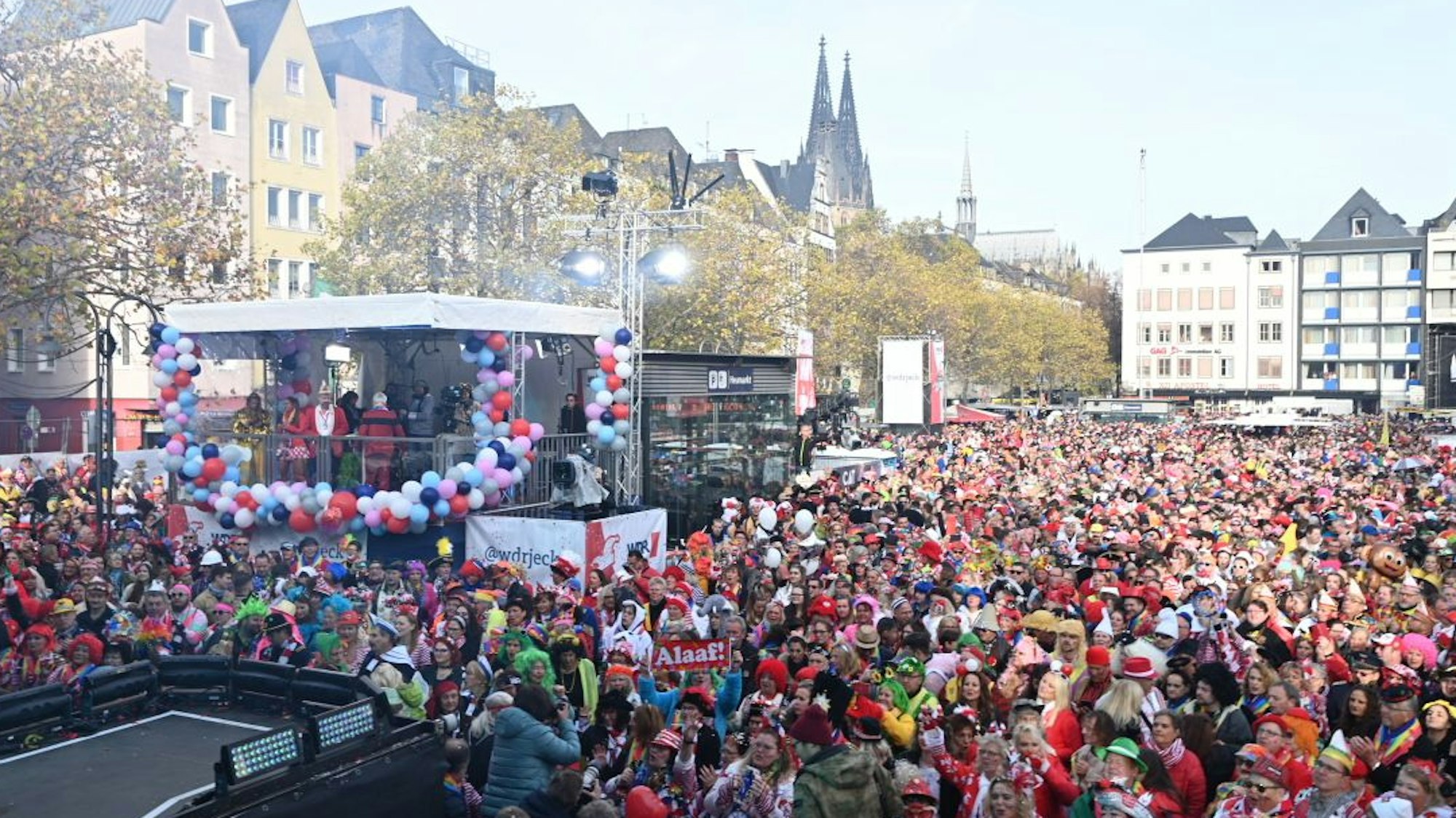 Eine Menschenmenge am Heumarkt, im Hintergrund weit entfernt der Kölner Dom.