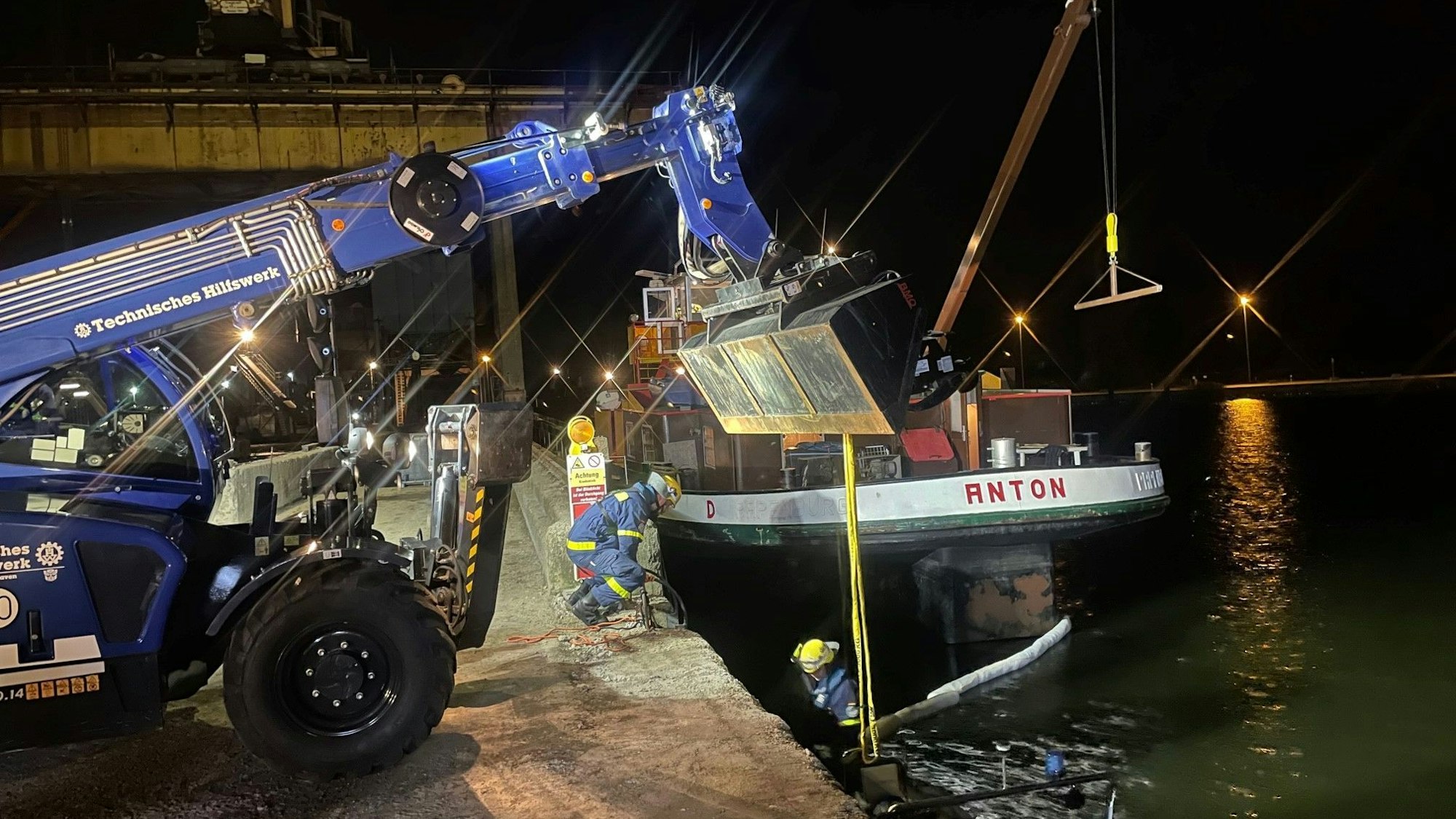 Einsatzkräfte und ein Spezialfahrzeug stehen rund um das havarierte Schiff „Anton“.