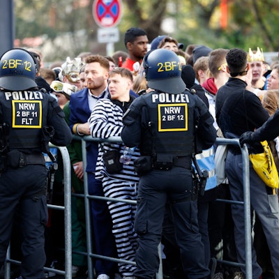 Karnevalisten stehen an einer Absperrung, da Polizeibeamte den Zugang zur Zülpicher Straße wegen Überfüllung abgeriegelt haben. Der Karnevalsauftakt zum 11.11. hat in Köln wie erwartet zu einem Massenandrang geführt