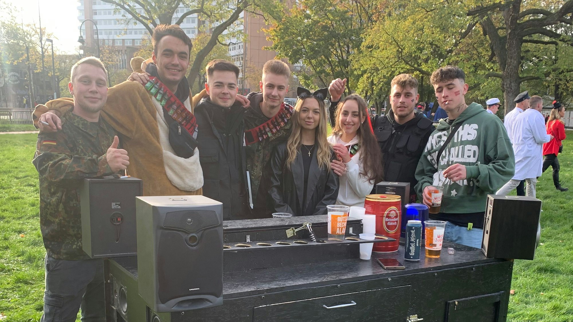 Mehrere junge Leute mit einer fahrbaren, schwarzen Box, darauf sind Getränke zu sehen.
