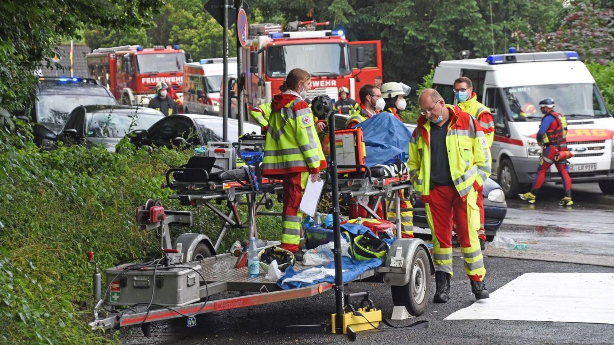Uniformierte Helfer der DLRG und des DRK stehen mit ihren Fahrzeugen beim Hochwasser-Einsatz am 15. Juli 2021 in Leichlingen auf der Straße.