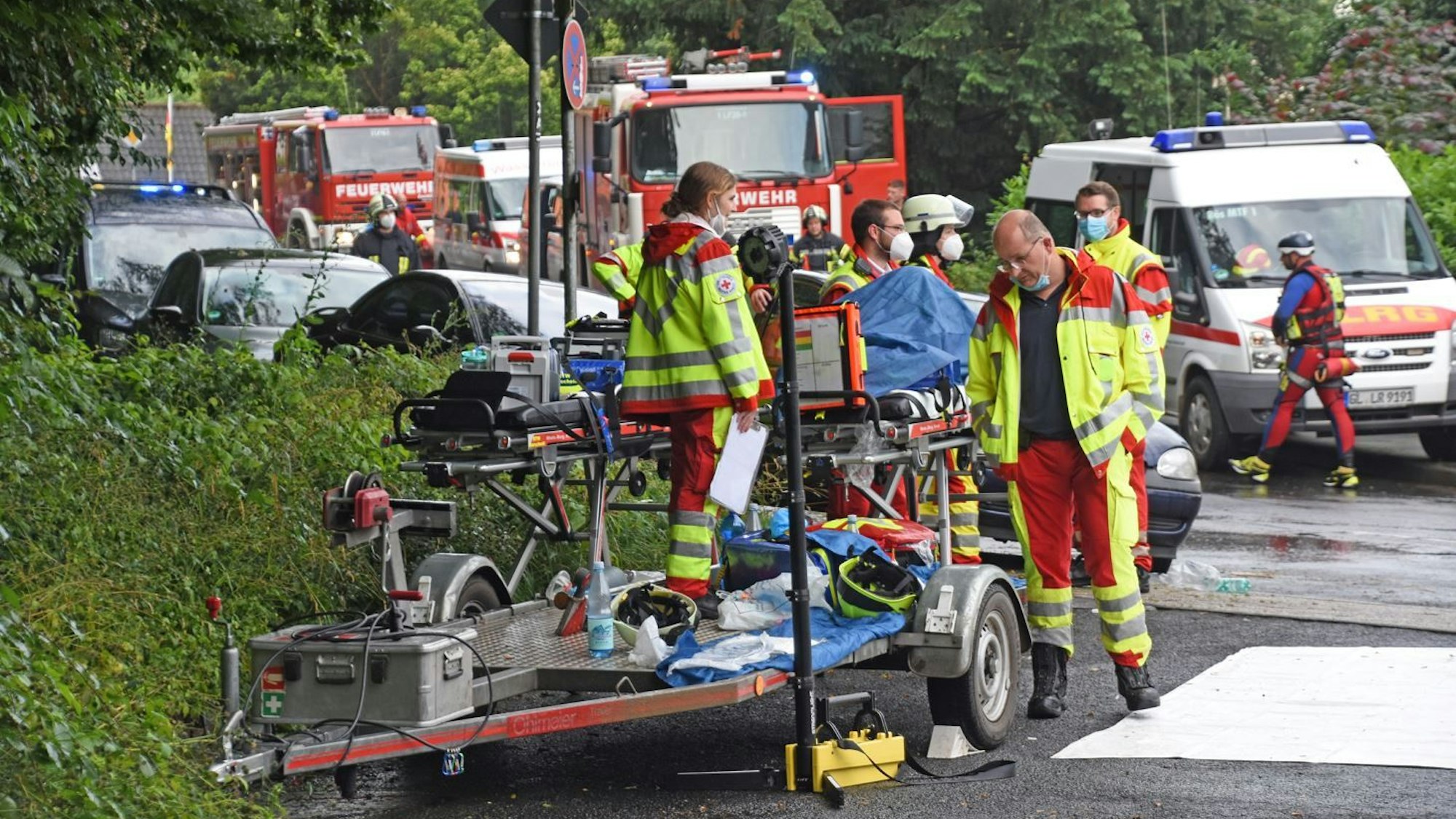 Uniformierte Helfer der DLRG und des DRK stehen mit ihren Fahrzeugen beim Hochwasser-Einsatz am 15. Juli 2021 in Leichlingen auf der Straße.