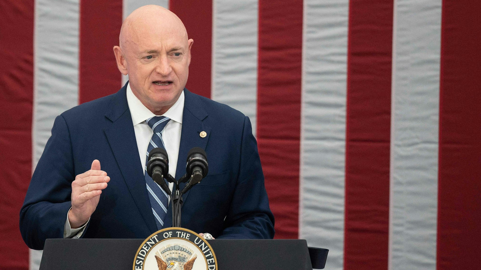 US-Senator Mark Kelly hält eine Rede vor einer amerikanischen Flagge.