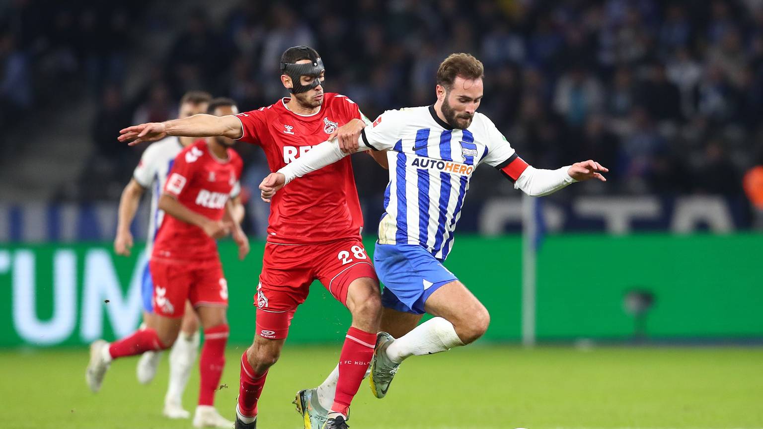 Lukas Tousart ist im Ballbesitz, Ellyes Skhiri kommt von hinten und will den Ball abnehmen. Im Hintergrund weitere Spieler.