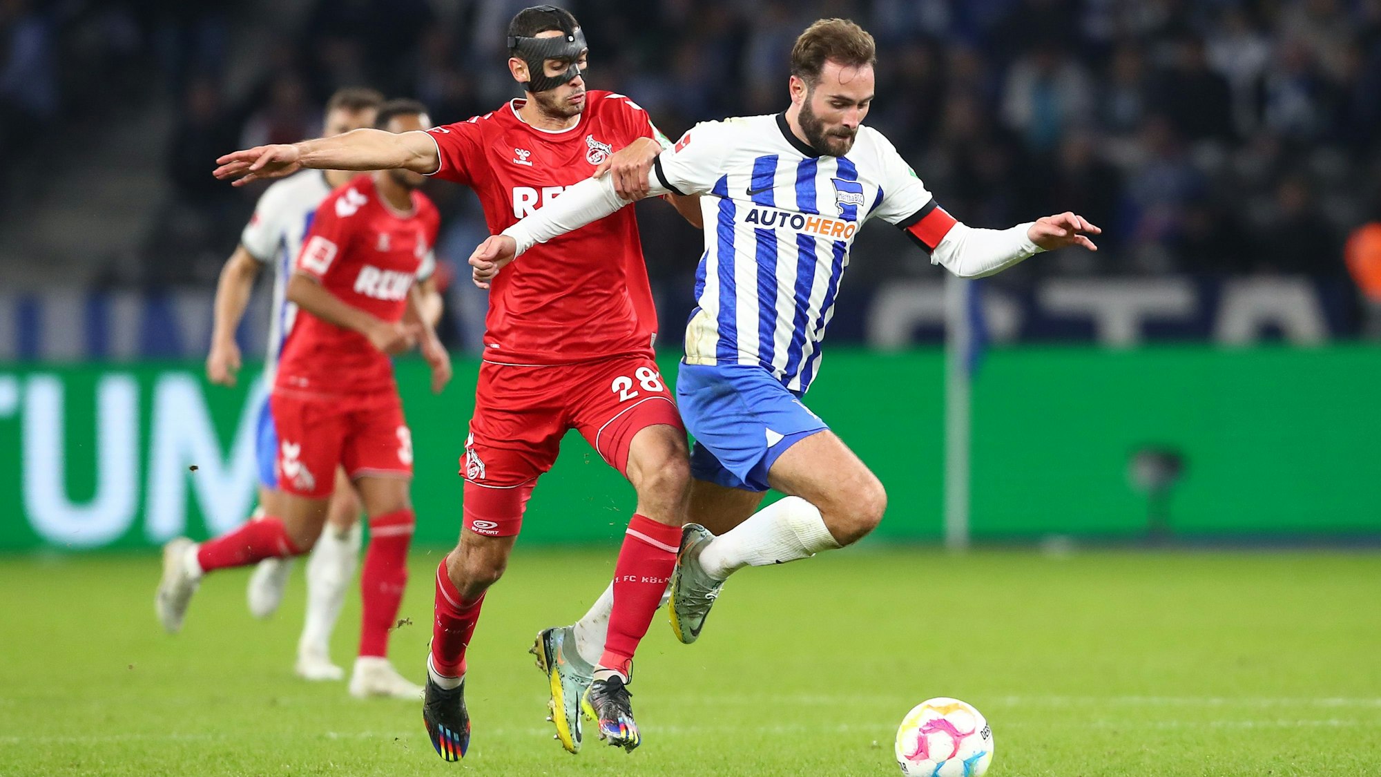 Lukas Tousart ist im Ballbesitz, Ellyes Skhiri kommt von hinten und will den Ball abnehmen. Im Hintergrund weitere Spieler.