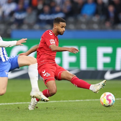 Linton Maina vom 1. FC Köln schießt den Ball. Maximilian Mittelstadt versucht den Ball abzuschirmen.