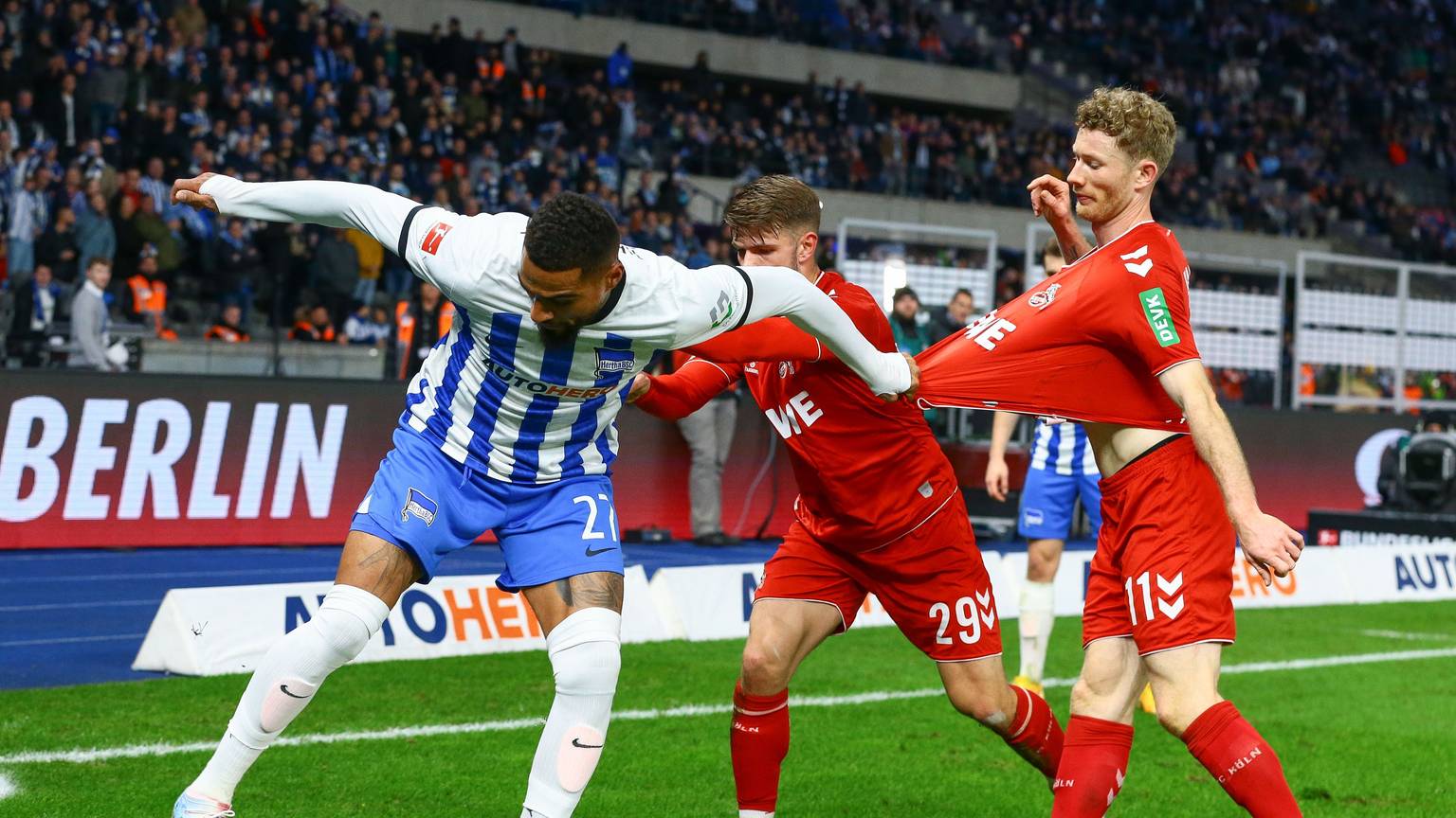 Boateng ist im Ballbesitz, Kainz neben ihm, Thielmann hinter ihm. Thielmann schubst Boateng, dieser hält sich am Shirt von Kainz fest. Sie befinden sich am Spielfeldrand, im Hintergrund sieht man die Zuschauertribünen.