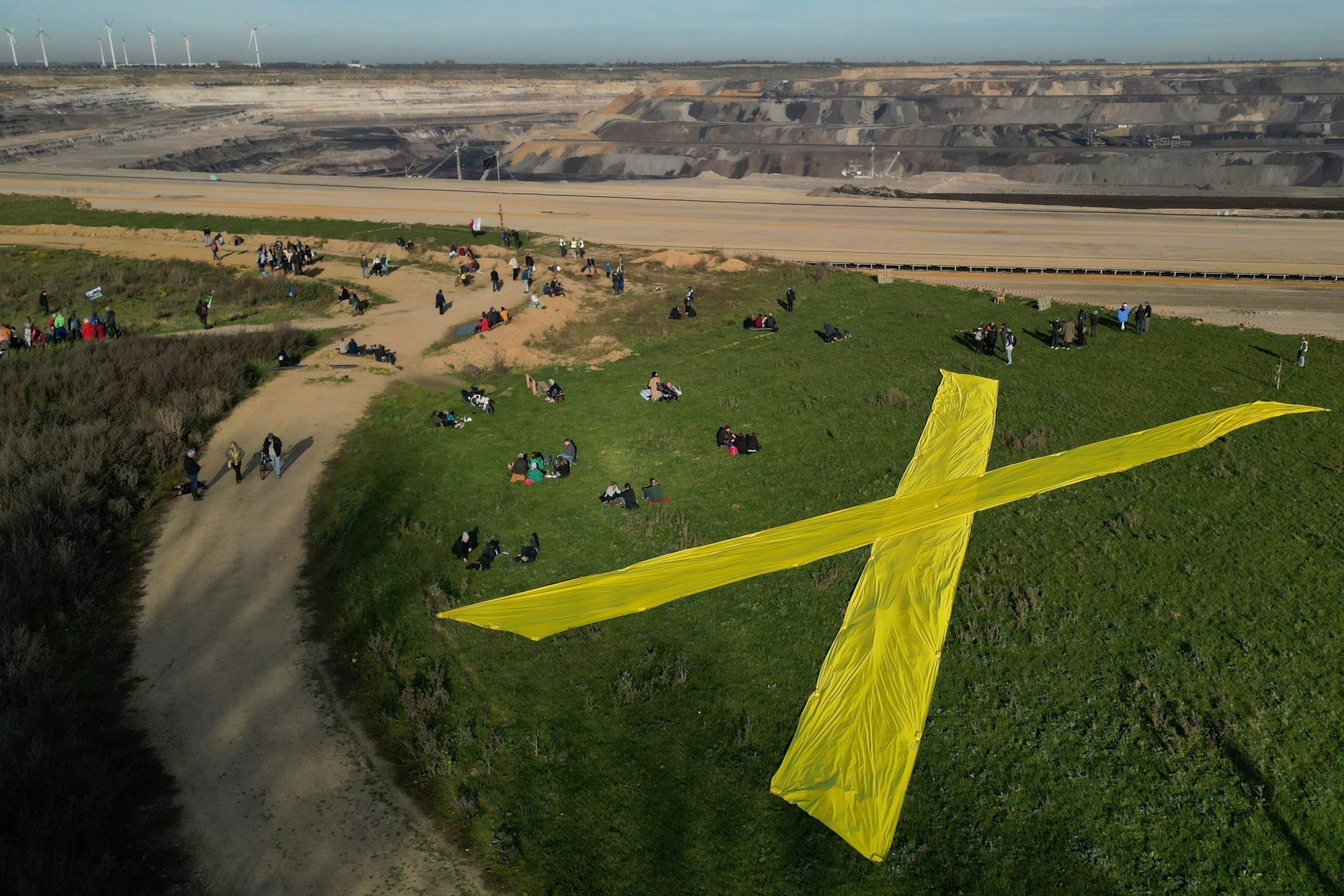 Eine Drohnenaufnahme zeigt ein großes gelbes X auf einem Feld vor Lützerath.