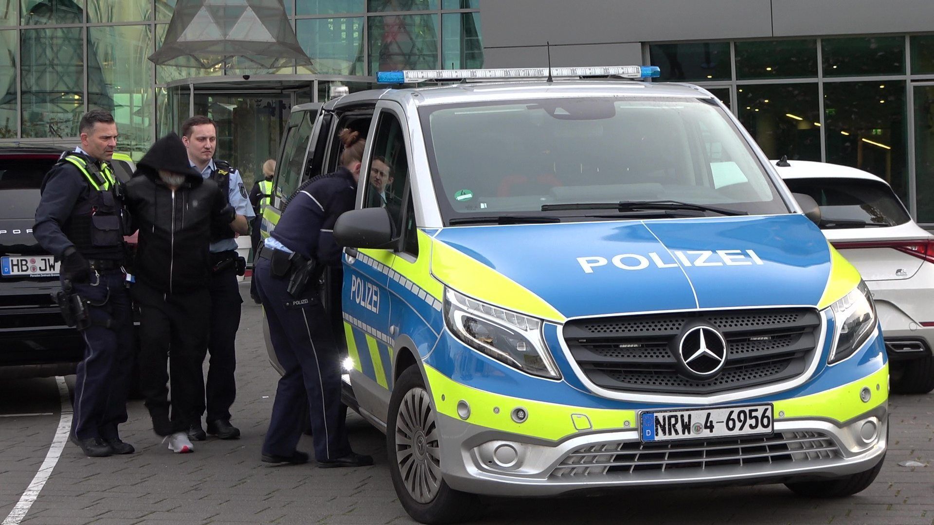 Polizeibeamte sind nach einer unklaren Bedrohungslage an einem Bonner Hotel im Einsatz und führen einen Mann ab und zu einem Polizeiauto.