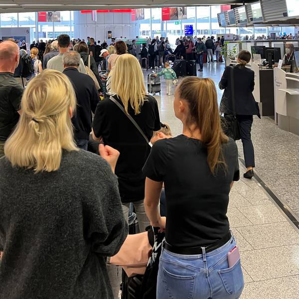 Ferienfluggäste stehen in einer langen Schlange am Frankfurter Flughafen.