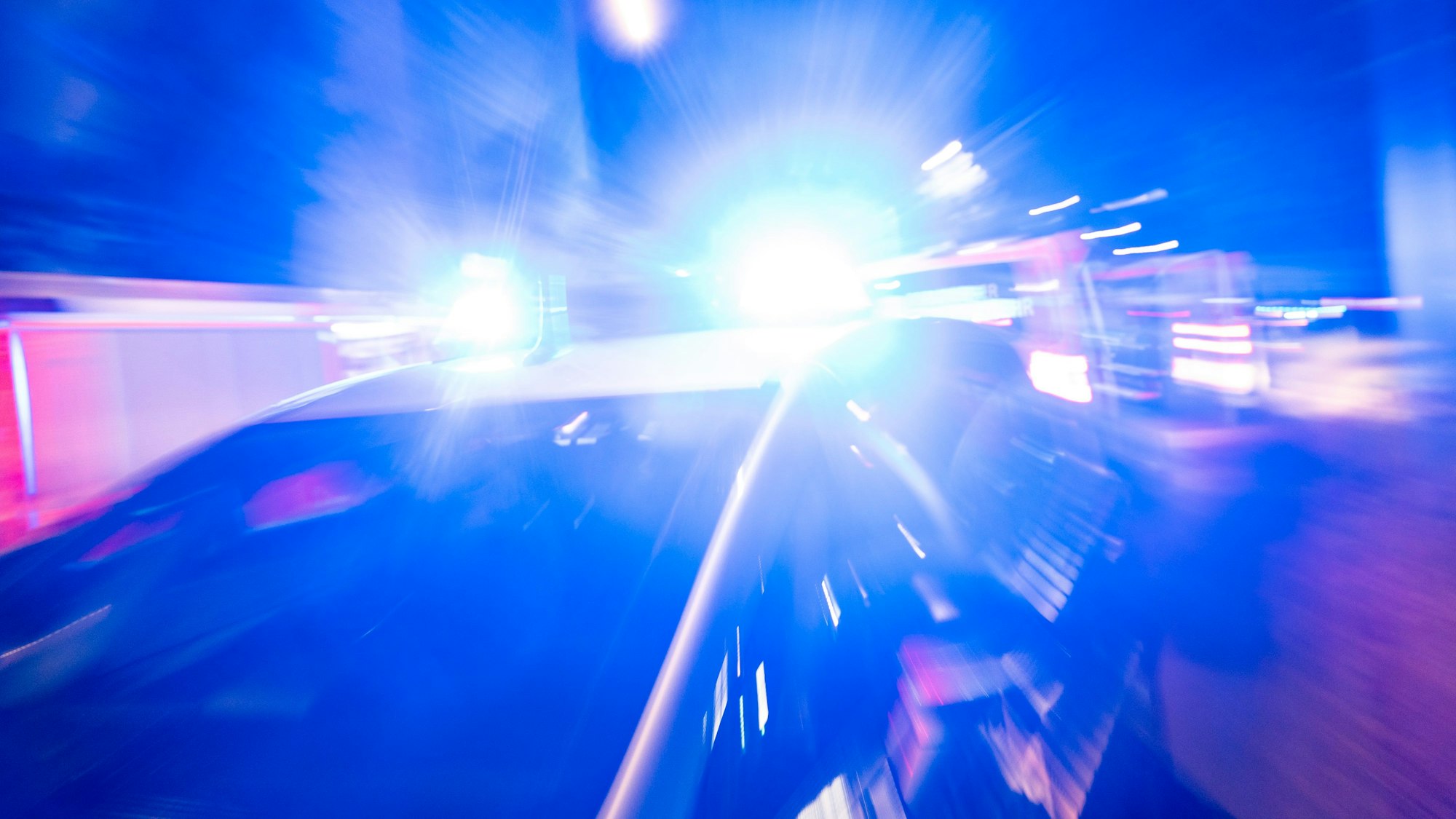 Ein Polizeiauto steht mit eingeschaltetem Blaulicht vor einem Hochhaus.