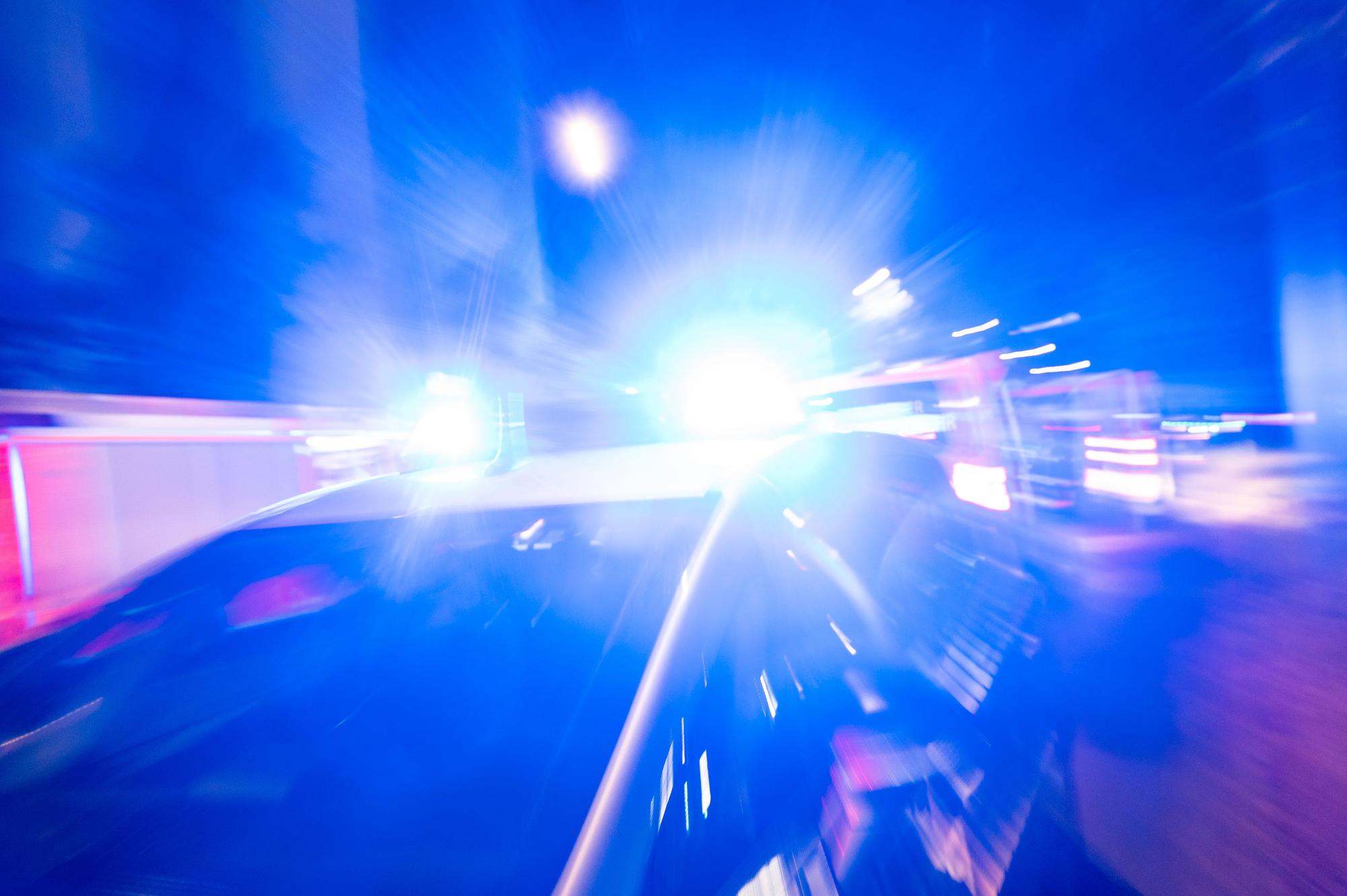 Ein Polizeiauto steht bei Nacht vor einem Haus, das Blaulicht leuchtet grell. Das Bild ist leicht verschwommen, Personen sind nicht zu sehen. (Symbolfoto)