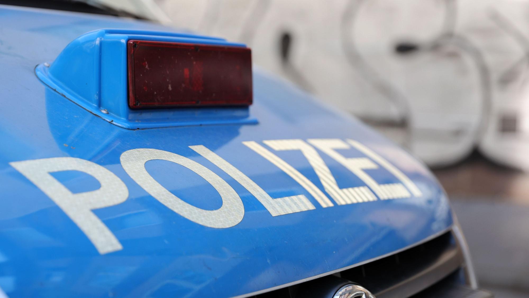Ein Polizeiwagen steht vor einer Mauer, auf die Graffiti gesprüht wurde.