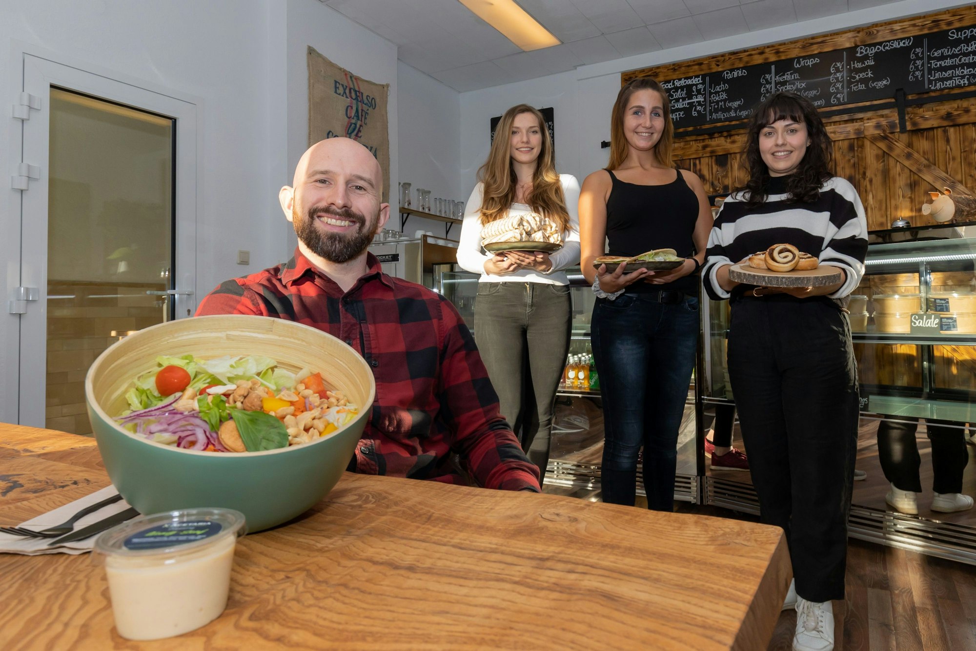 Gastronom Andreas Dauns und seine Mitarbeiterinnen zeigen eine Bowl und andere Speisen aus der Acetaria.