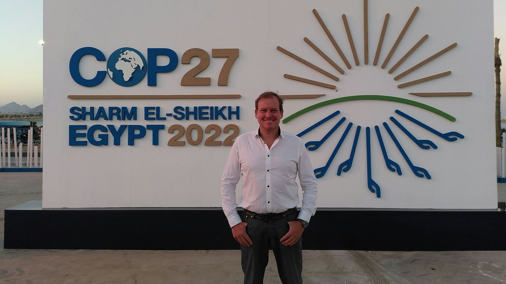 Sven Harten aus Drinhausen steht vor dem Schild der COP27 in Ägypten.