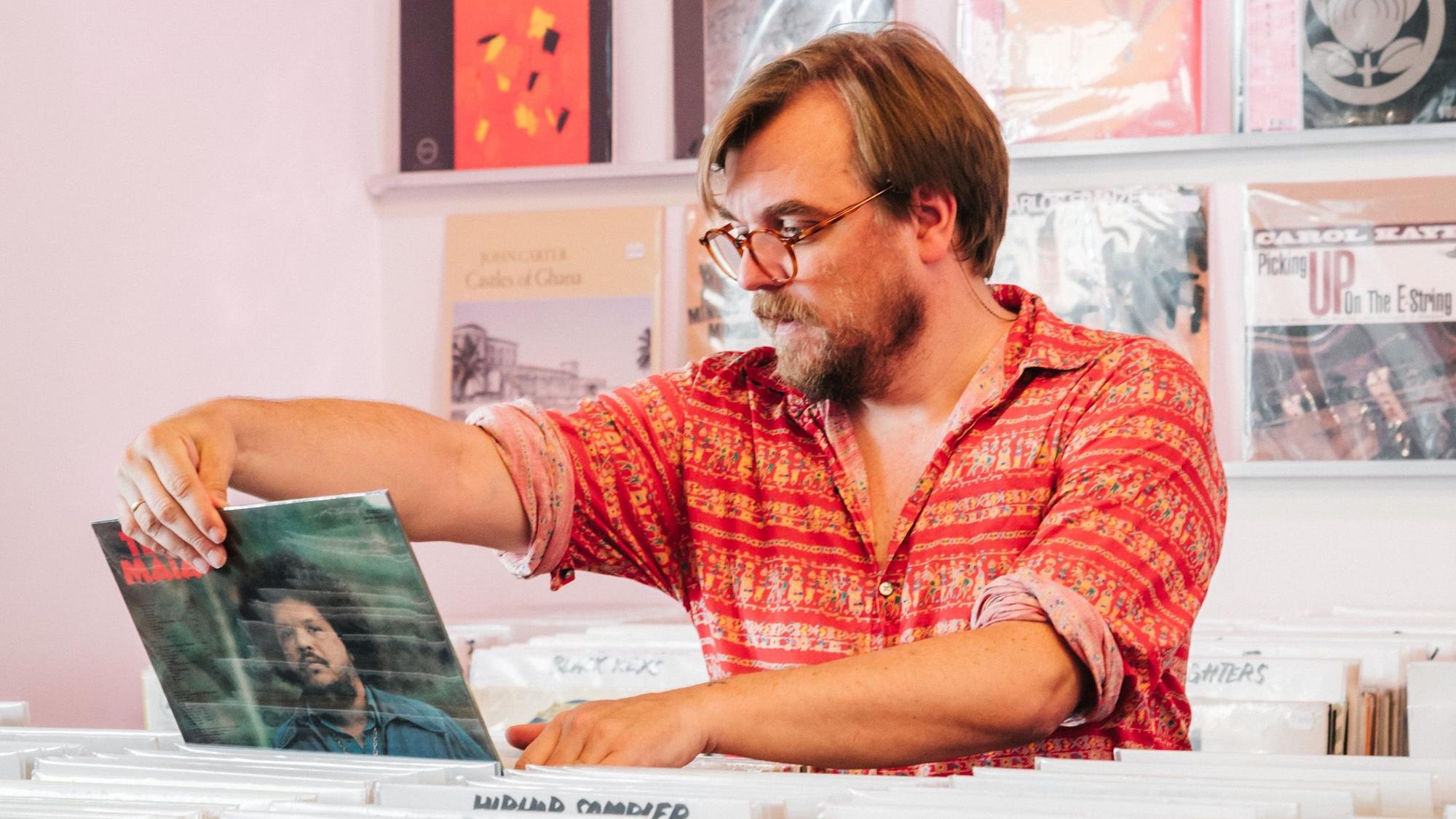 Nilz Bokelberg betrachtet in einem Schallplattenladen ein Plattencover.