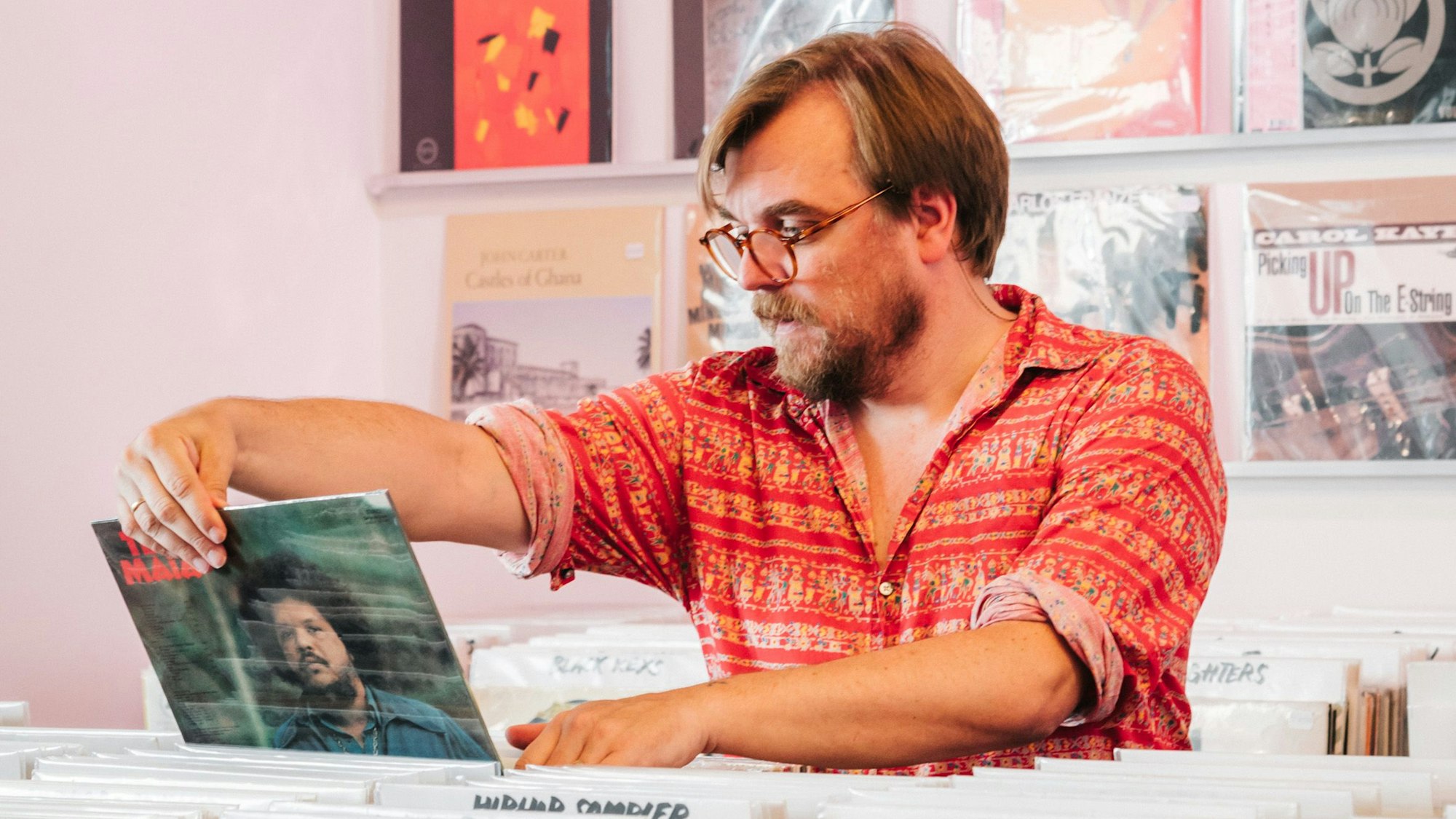 Nilz Bokelberg betrachtet in einem Schallplattenladen ein Plattencover.