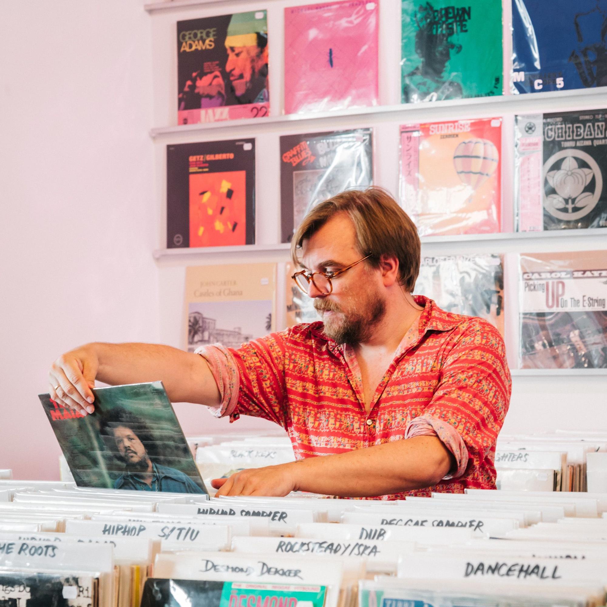 Nilz Bokelberg betrachtet ein Schallplattencover in einem Plattenladen.