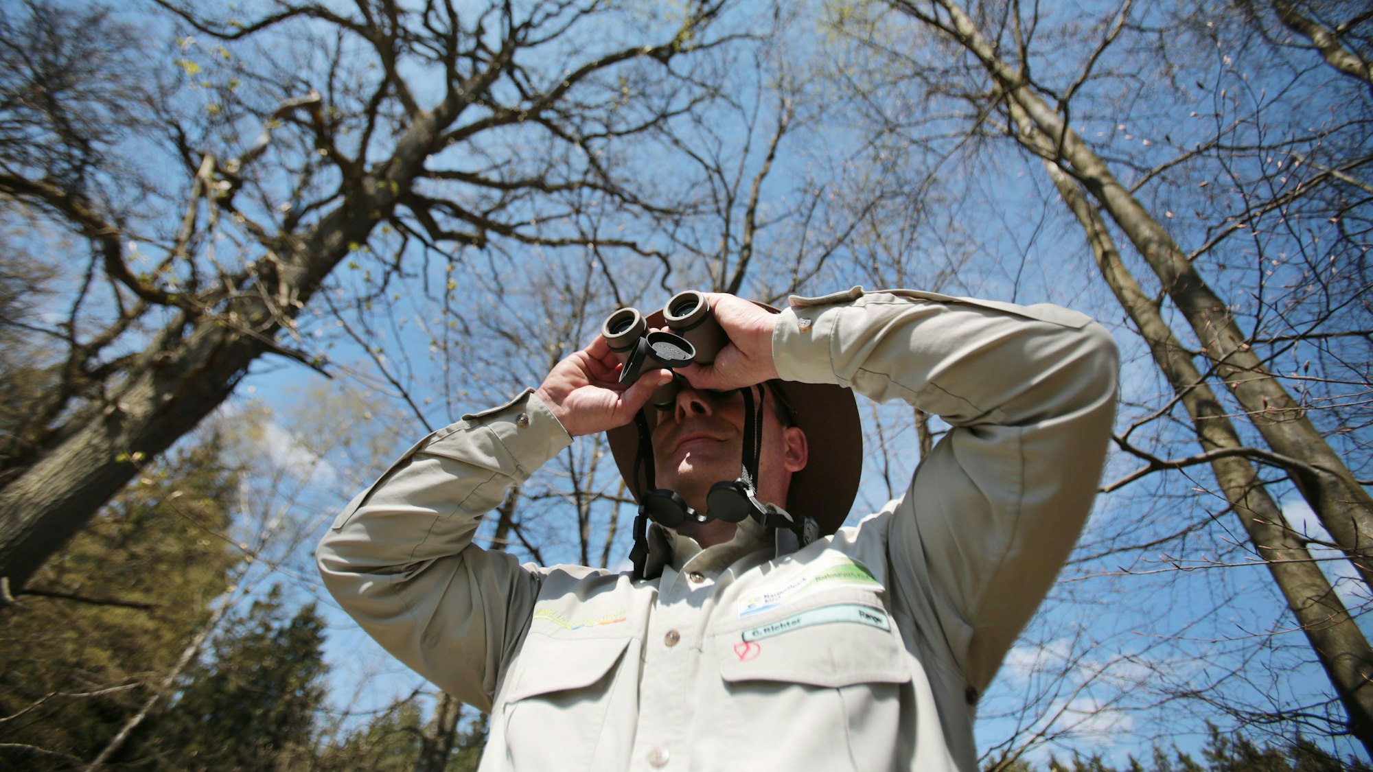 Der Ranger Carsten Richter blickt im Nationalpark Eifel in Schleiden durch den Feldstecher.