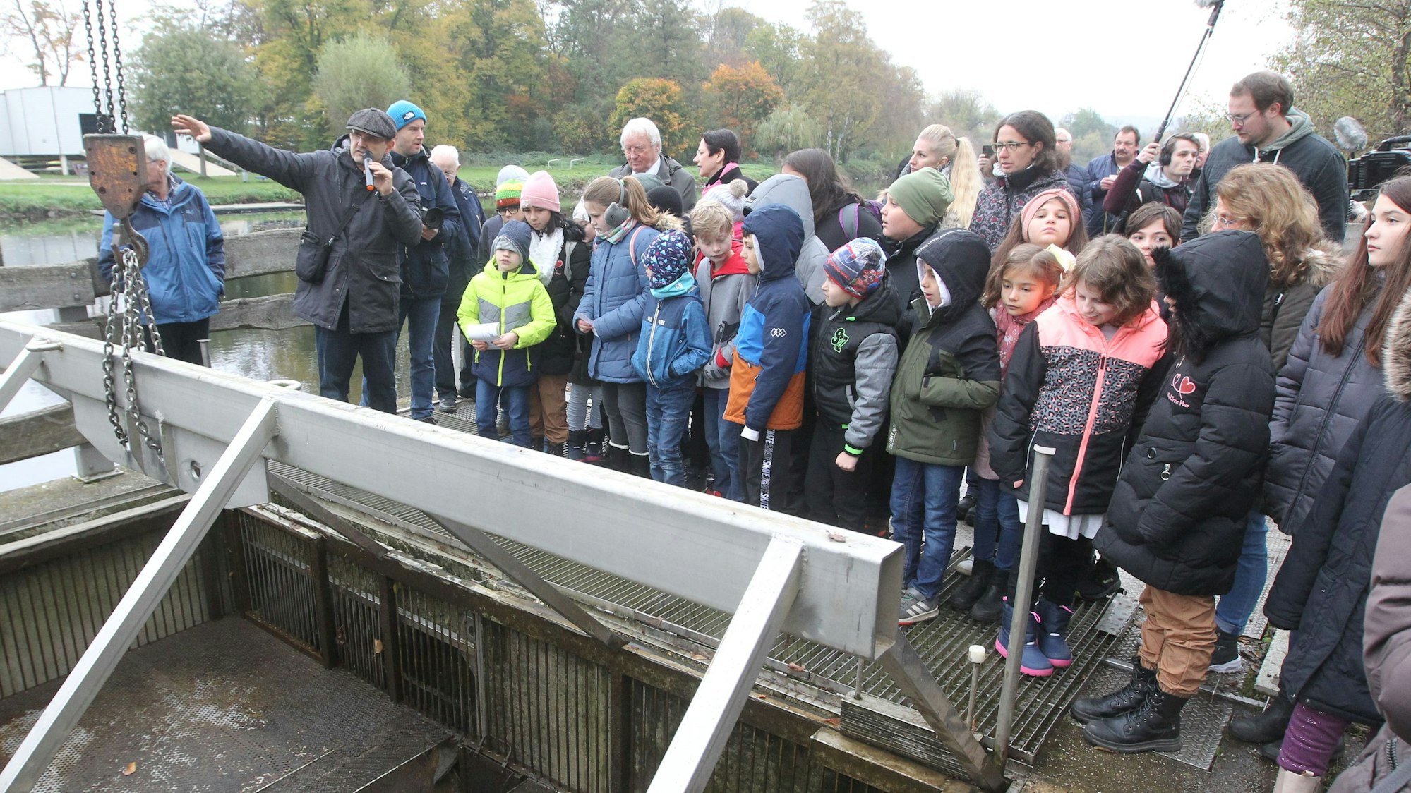 Schüler und NRW-Landwirtschaftsministerin Silke Görißen stehen am Siegwehr in Sankt Augustin-Buisdorf.