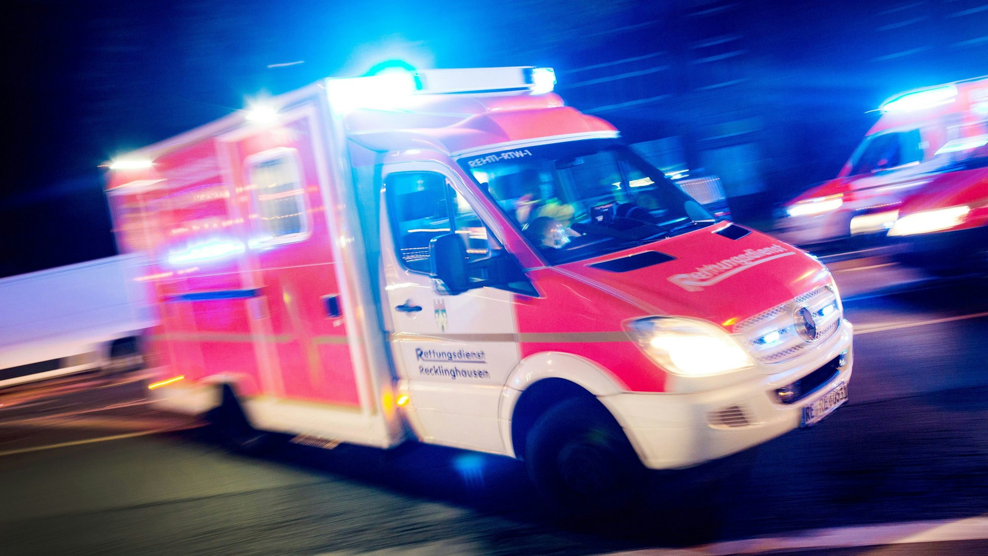 Ein Rettungswagen der Feuerwehr fährt mit Blaulicht durch eine Straße.