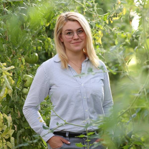 Caroline Uhl steht inmitten grüner Pflanzen.
