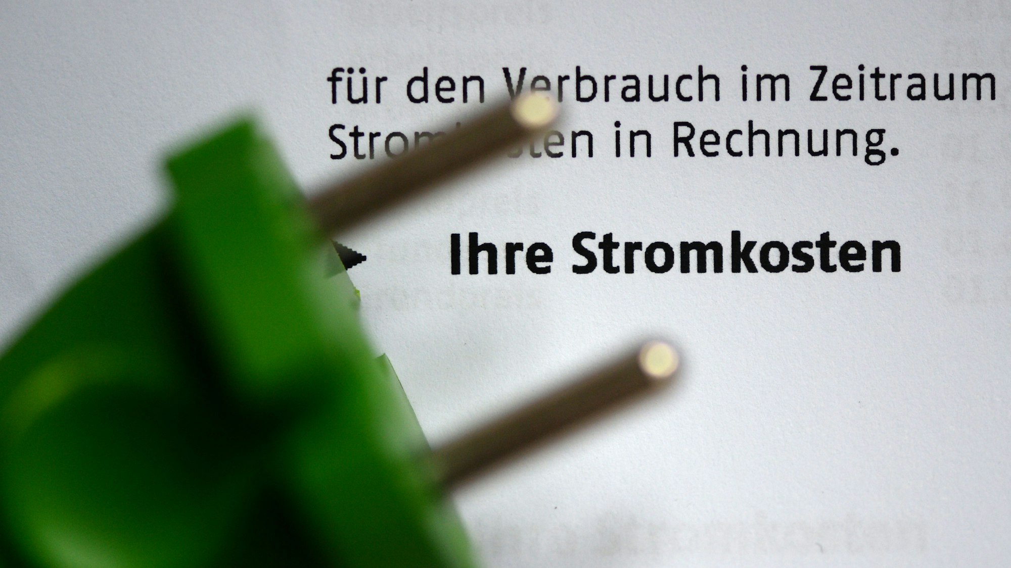Ein grüner Stromstecker auf einer Stromrechnung.