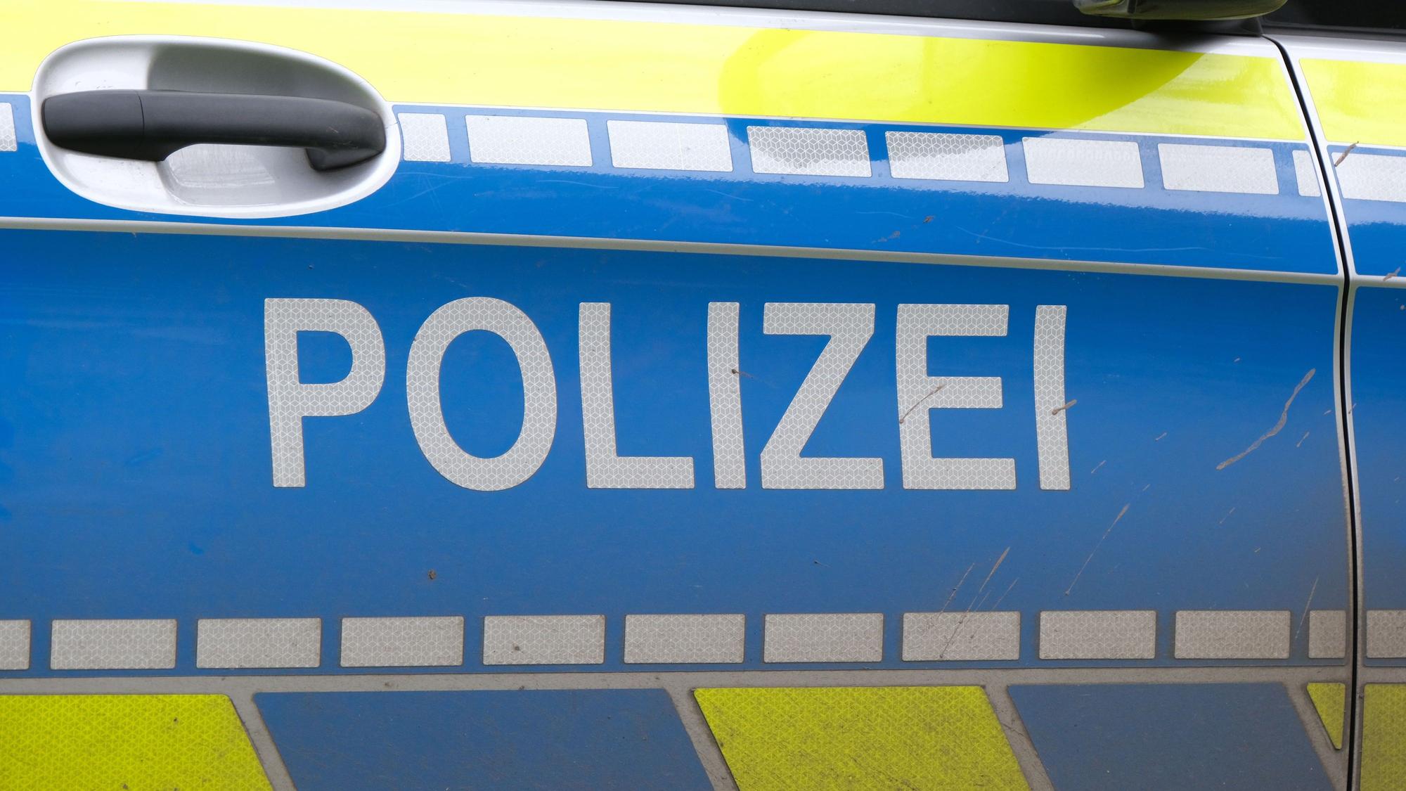 Auf der Türe eines Polizeiautos ist der Schriftzug „Polizei“ zu lesen.