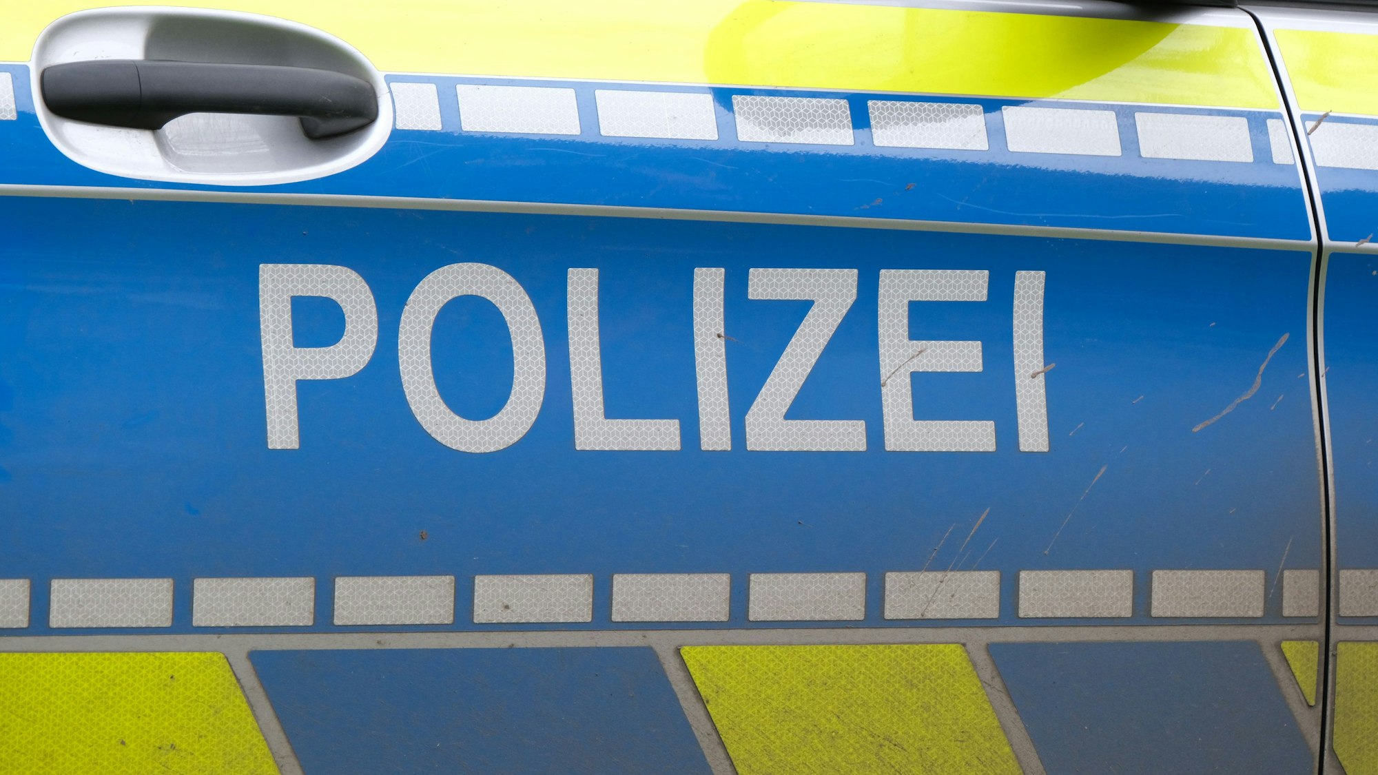 Ansicht auf Tür eines Polizeiautos mit der Aufschrift „Polizei“.