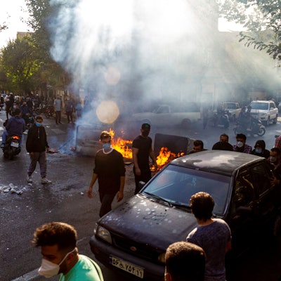 Menschen protestieren in Teheran auf der Straße und haben Barrikaden errichtet. Es brennen Feuer. Viele Demonstranten tragen Gesichtsmasken.