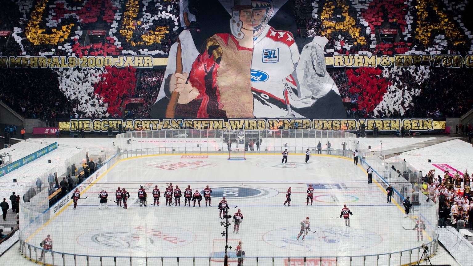 Das Rhein-Energie-Stadion während des Winter-Games 2019. Auf dem Platz sieht man die Mannschaften, auf den Rängen haben Fans eine Choreografie vorbereitet.