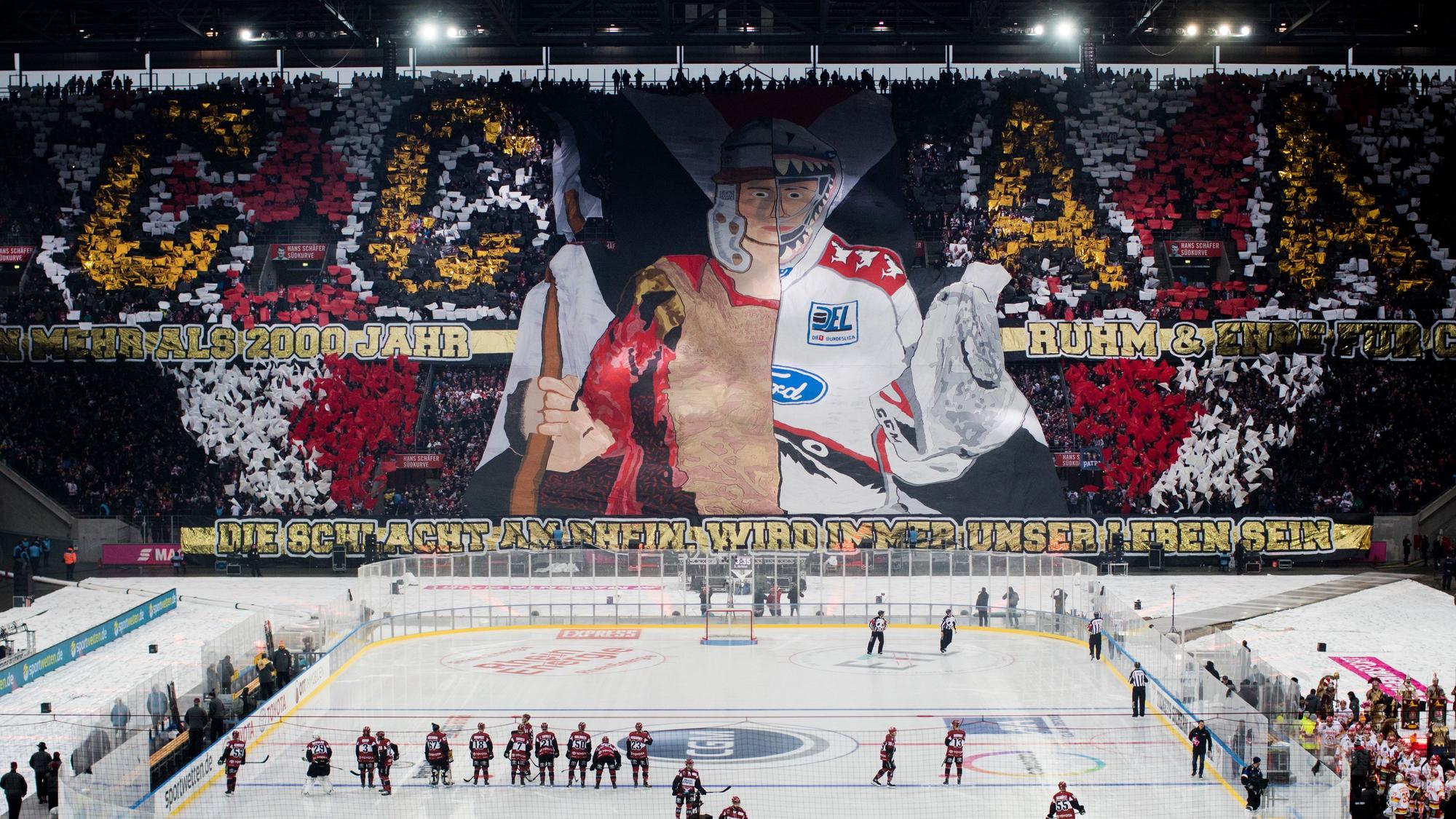Das Rhein-Energie-Stadion während des Winter-Games 2019. Auf dem Platz sieht man die Mannschaften, auf den Rängen haben Fans eine Choreografie vorbereitet.
