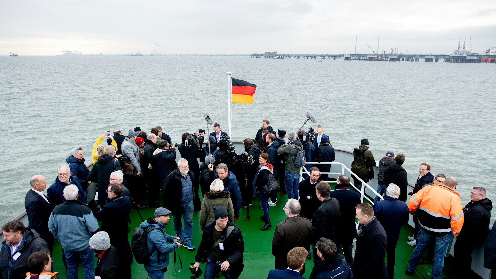 15.11.2022, Niedersachsen, Wilhelmshaven: Zahlreiche Medienvertreter und Ehrengäste stehen auf einem Schiff vor dem Anleger für das LNG-Terminal in der Nordsee vor Wilhelmshaven.