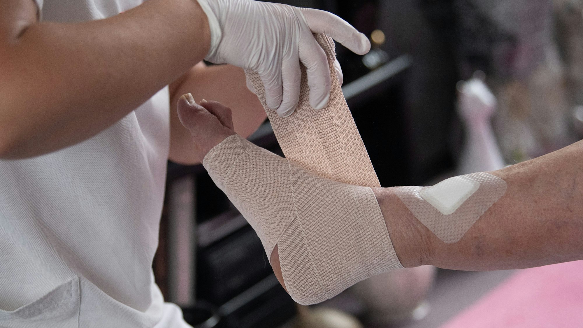 Eine Pflegefachkraft legt einen Kompressionsverband an einem Fuß an.