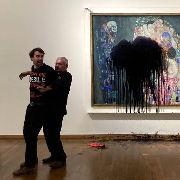 Ein Sicherheitsmann trägt einen Klima-Aktivisten von einem Klimt-Gemälde weg, auf das zuvor Öl geworfen wurde. Ein zweiter Aktivist steht neben dem Bild, auf dem ein großer Ölfleck klafft, das Bild wurde durch eine Glasscheibe geschützt.