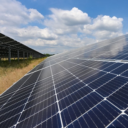 Zu sehen ist ein Solarpark mit großen schräg aufgestellten Photovoltaikflächen.