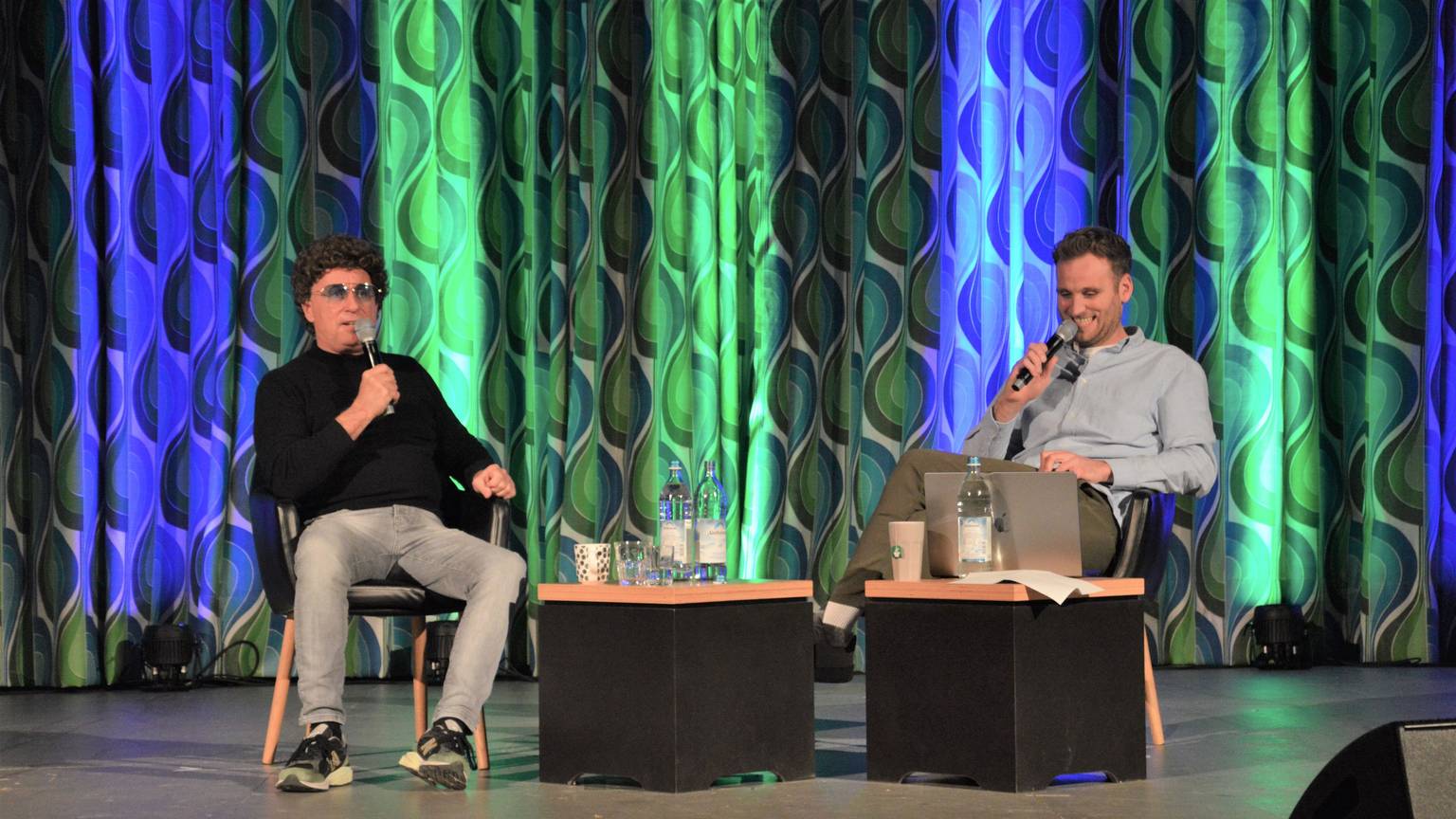 Atze Schröder (l.) und Leon Windscheid sitzen auf der Bühne im Kino in Schleiden-Vogelsang.