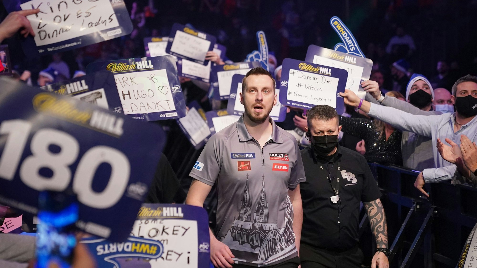 Der Dartspieler Florian Hempel läuft bei der Darts-WM in die Londoner Arena ein und wird von Fans bejubelt.