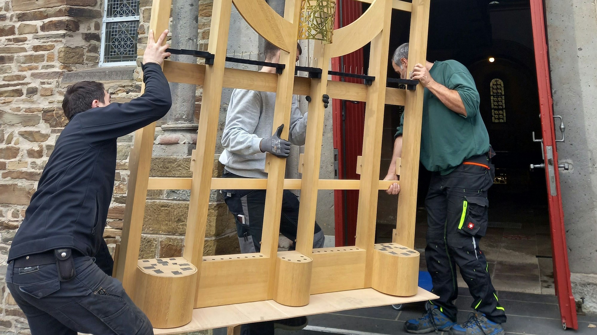 Arbeiter tragen ein Gerüstteil in die Basilika in Morsbach.