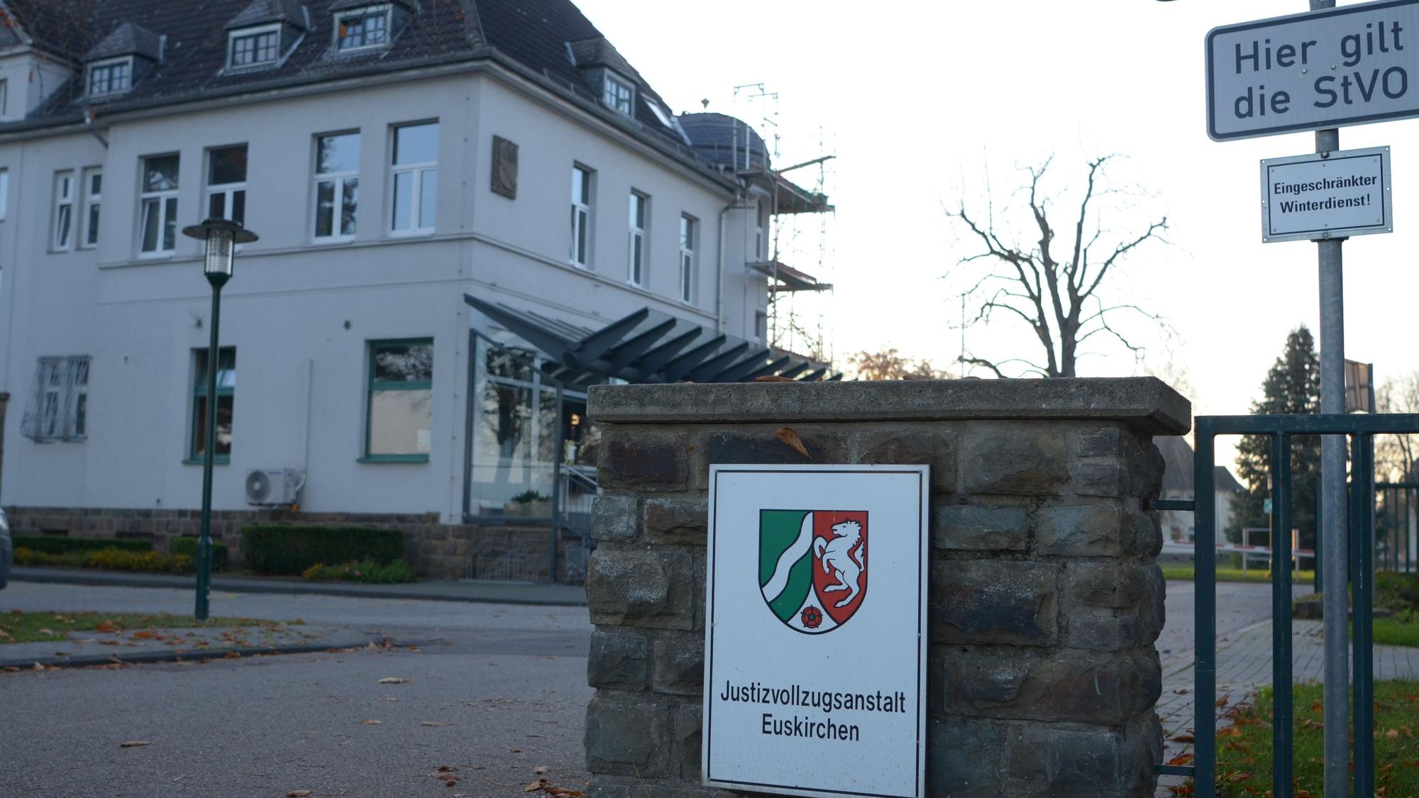 Am Eingang der Justizvollzugsanstalt Euskirchen hängt ein Schild mit dem Wappen des Landes NRW. Im Hintergrund sieht man ein Gebäude.